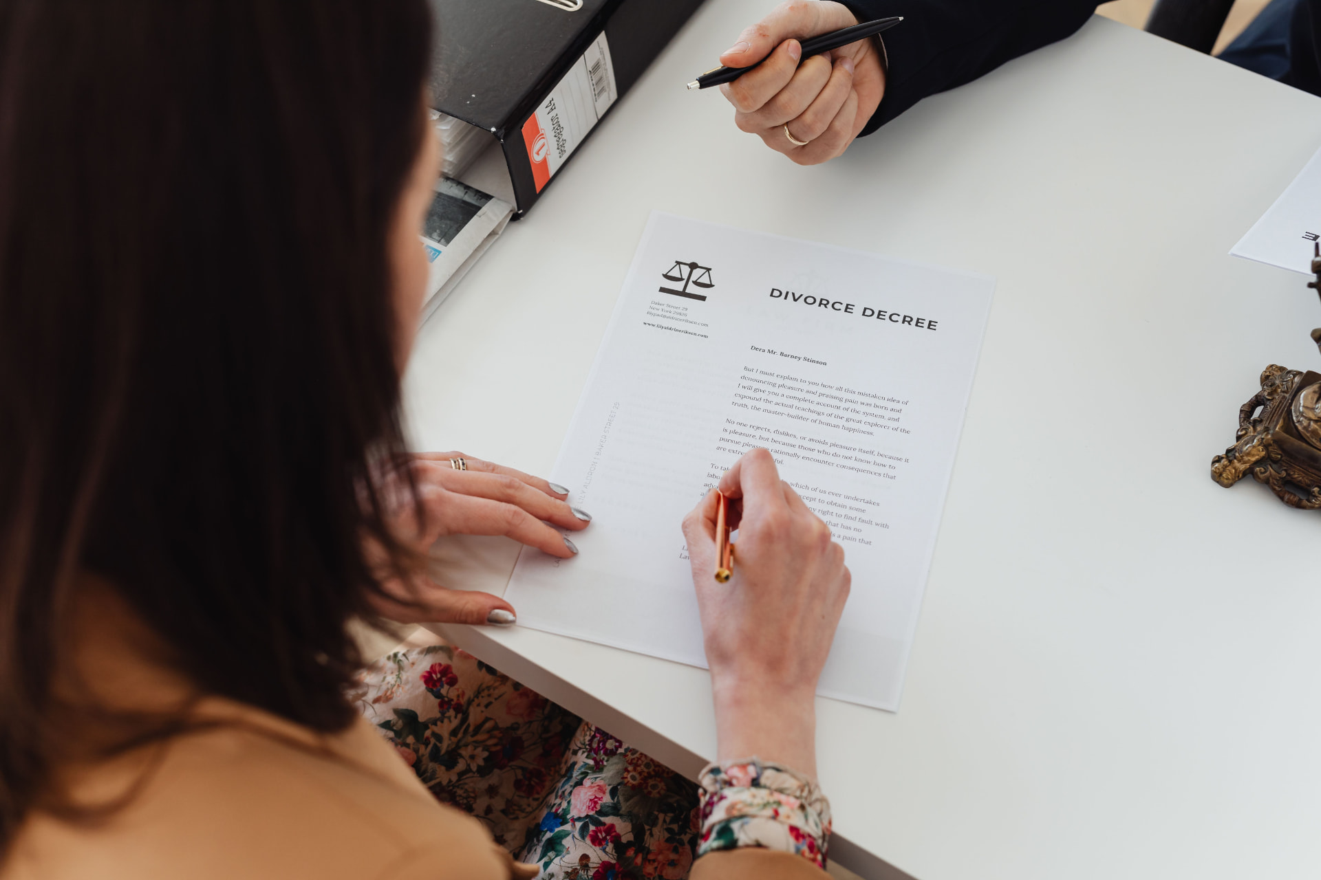 Two people signing a divorce decree across a conference table